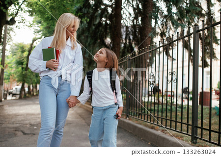 Smiling, positive emotions. Schoolgirl with her mother are outdoors together 133263024