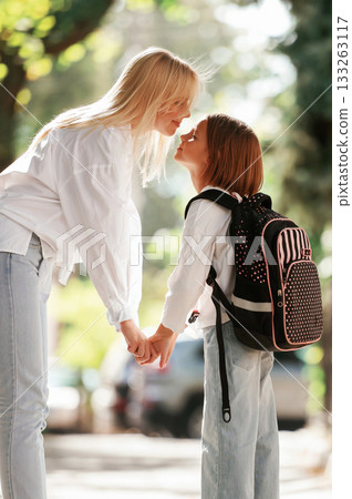 Holding the hands. Schoolgirl with her mother are outdoors together 133263117