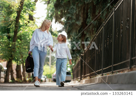 Leading the daughter to school. Little girl with her mother are outdoors together 133263141