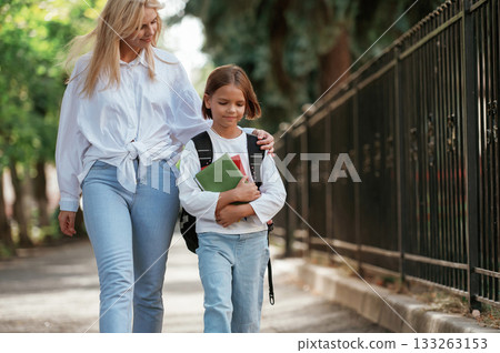 Smiling, positive emotions. Schoolgirl with her mother are outdoors together 133263153