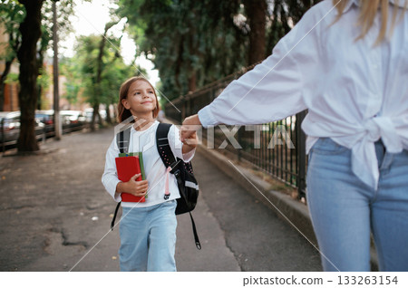 Schoolgirl with her mother are outdoors together 133263154