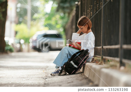 On the sidewalk. Schoolgirl with backpack is outdoors 133263198