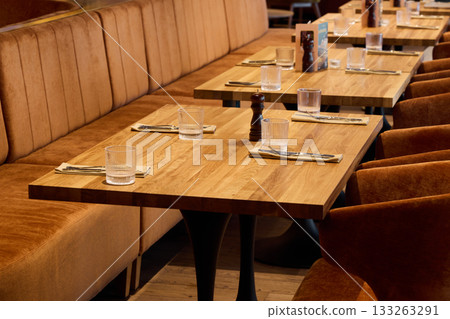 informal communal area with warm decor, shared wooden tables with soft seating and inviting ambiance 133263291