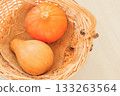 Orange pumpkins in a wicker basket. Fall colors and still life. Warm tones. Top view. 133263564