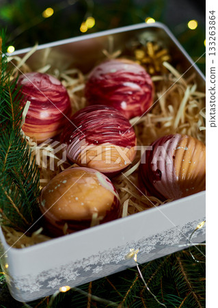 Delightful Assorted Dessert Spheres Displayed in a Gift Box Surrounded by Festive Greenery and Decorative Accents Delightful Assorted Dessert Spheres Displayed in a Gift Box Surrounded by Festive Greenery and Decorative Accents 133263864