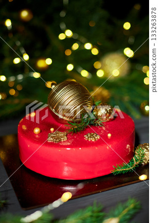 Festive Red Cake Adorned With Golden Decorations and Greenery, Set Against a Backdrop of Sparkling Lights During a Holiday Celebration Festive Red Cake Adorned With Golden Decorations and Greenery, Set Against a Backdrop of Sparkling Lights During a Holiday Celebration 133263878