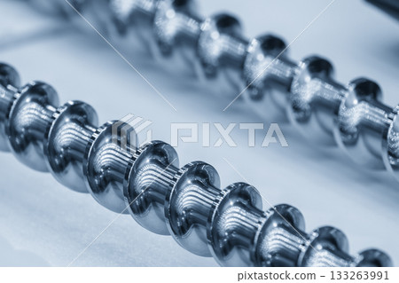 Close up scene body of the barrel screw of injection machine spare parts in the light blue scene. Close up scene body of the barrel screw of injection machine spare parts in the light blue scene. 133263991