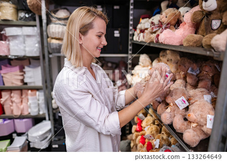 Woman choosing a teddy bear in a gift shop warehouse Woman choosing a teddy bear in a gift shop warehouse 133264649