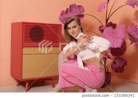 Stylist portrait woman wearing pink trousers by cabinet 133266341