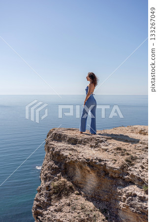 Woman cliff ocean view standing on high rocky edge admiring the vast horizon 133267049