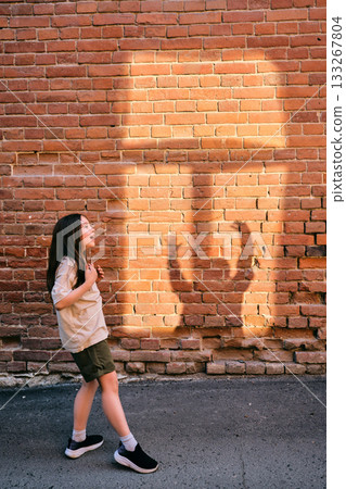 Girl playing shadow games on brick wall 133267804