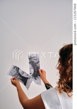 Woman holding pieces of a torn black and white portrait Woman holding pieces of a torn black and white portrait 133267808