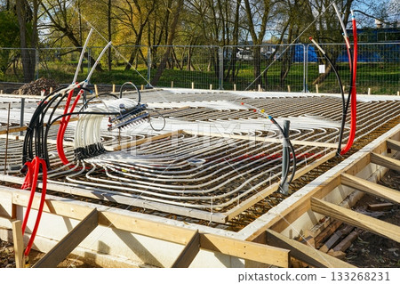 Underfloor heating system installation with plastic pipes in concrete base, house construction site Underfloor heating system installation with plastic pipes in concrete base, house construction site 133268231