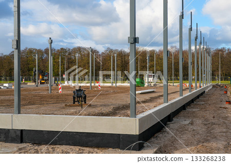 Steel frame columns installed on concrete foundation at large commercial construction site 133268238