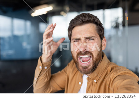 Furious businessman shouting in an office, overwhelmed by stress and frustration, mouth wide open as he vents anger and exhaustion from work pressure and burnout Furious businessman shouting in an office, overwhelmed by stress and frustration, mouth wide open as he vents anger and exhaustion from work pressure and burnout 133268354