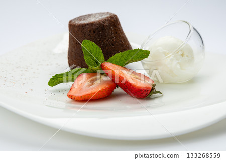 Chocolate lava cake with vanilla ice cream and strawberries on white plate, top view 133268559