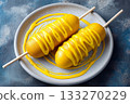 Two golden corndogs on sticks drizzled with yellow mustard, served on a white plate with a blue textured background 133270229