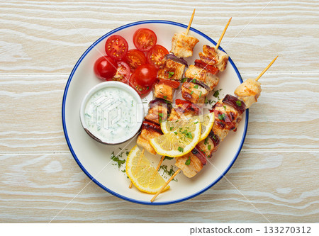 Grilled chicken skewers with lemon wedges, cherry tomatoes and yogurt sauce top view Grilled chicken skewers with lemon wedges, cherry tomatoes and yogurt sauce top view 133270312