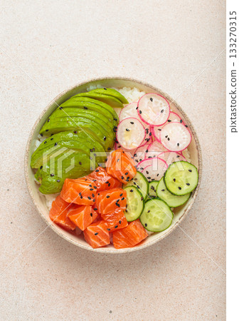 Salmon poke bowl with avocado, radish, cucumber and rice on light beige background top view Salmon poke bowl with avocado, radish, cucumber and rice on light beige background top view 133270315