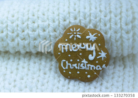 Gingerbread cookie decorated with royal icing on white knitted background. Merry Christmas Gingerbread cookie decorated with royal icing on white knitted background. Merry Christmas 133270358