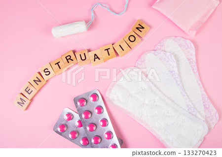 Sanitary pads, tampons, pills on pink background. Set of feminine hygiene products for menstruation. Womens health concept. Wooden lettering. 133270423