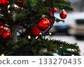 Red Christmas balls and garlands on branch. Christmas tree with decor. Holiday season, street decorations. 133270435