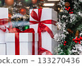 Gift boxes in store window. Season of Christmas shopping and sales. White boxes with red ribbons on background of Christmas decorations. 133270436
