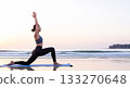Woman in yoga pose on beach at sunrise with ocean waves image 133270648