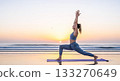 Woman practicing warrior pose yoga on beach at sunrise ocean 133270649