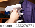 Handheld Steamer Ironing Purple Shirt in White Glove at Home 133270771