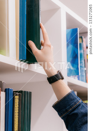 close-up of woman shelves in library, student chooses book. library is filled with books. close-up of woman shelves in library, student chooses book. library is filled with books. 133271065
