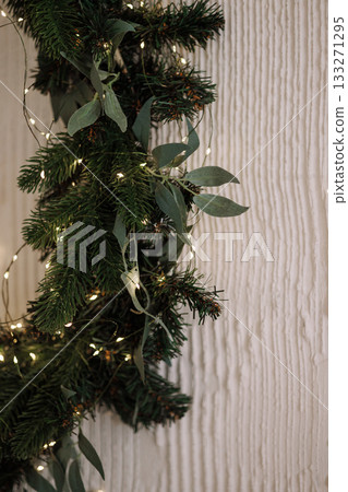 Christmas garland with lights and pearls on white fireplace and beige wall 133271295