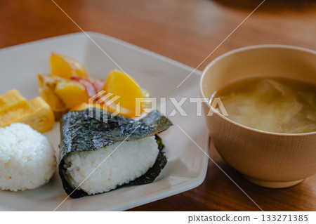 A Japanese breakfast of rice balls, tamagoyaki (rolled egg), fried potatoes, and miso soup 133271385