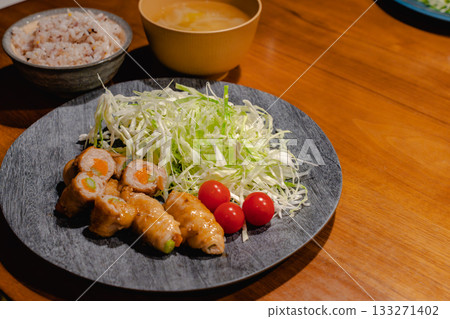 A home-style dinner of pork wrapped in vegetables, shredded cabbage, mixed grain rice, and miso soup A home-style dinner of pork wrapped in vegetables, shredded cabbage, mixed grain rice, and miso soup 133271402
