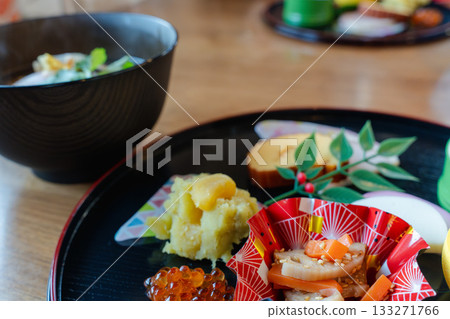 A gorgeous New Year's dinner table with ozoni and osechi dishes arranged on a half-moon tray 133271766