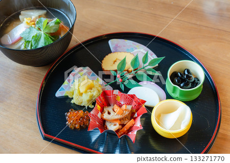 A gorgeous New Year's dinner table with ozoni and osechi dishes arranged on a half-moon tray 133271770