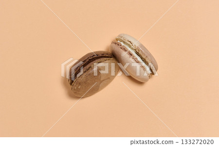 Two brown macarons on beige background, top view 133272020