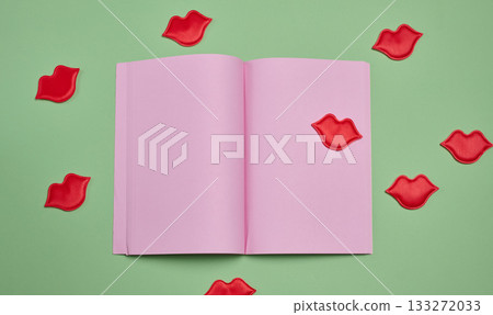 An open notebook with blank pink pages surrounded by red lip appliques on a green background An open notebook with blank pink pages surrounded by red lip appliques on a green background 133272033