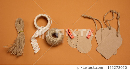 Set of packaging and decorative materials: twine, lace ribbon, twine, craft tags, and clothespins on a brown background Set of packaging and decorative materials: twine, lace ribbon, twine, craft tags, and clothespins on a brown background 133272050