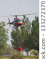 Helicopter in Action with Water Bucket Fighting Fire 133272370