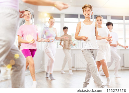 Male boy student repeats movements of unrecognizable teacher during group modern dance class. Male boy student repeats movements of unrecognizable teacher during group modern dance class. 133272858