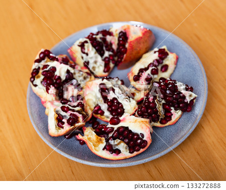 Pieces of ripe pomegranate on a plate top view 133272888