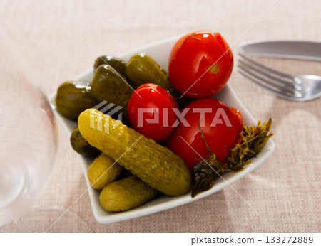 Portion of pickled tomatoes and cucumbers is served on plate with dill Portion of pickled tomatoes and cucumbers is served on plate with dill 133272889