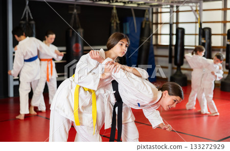Teenage girls in white kimono at karate lesson Teenage girls in white kimono at karate lesson 133272929