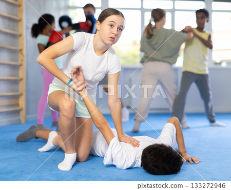 Self-defense - girl twists the arm of an attacking boy during self defense training Self-defense - girl twists the arm of an attacking boy during self defense training 133272946