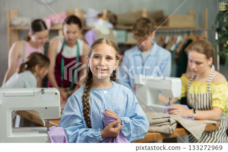Teenage girl happily shows off a t-shirt he sewed with his own hands on sewing machine 133272969