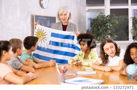 Mature female teacher tells the pupils the history of Uruguay 133272971