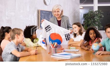 Female teacher showing south korean flag to kids in geography class 133272980