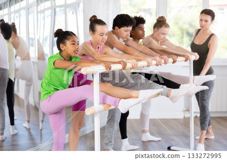 Group of teenage dancers practicing stretching at barre 133272995