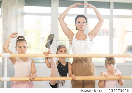 Choreography teacher posing with little girl students in ballet studio Choreography teacher posing with little girl students in ballet studio 133273026